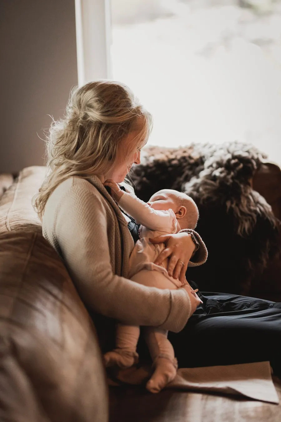 Moeder geeft borstvoeding aan haar baby op de bank